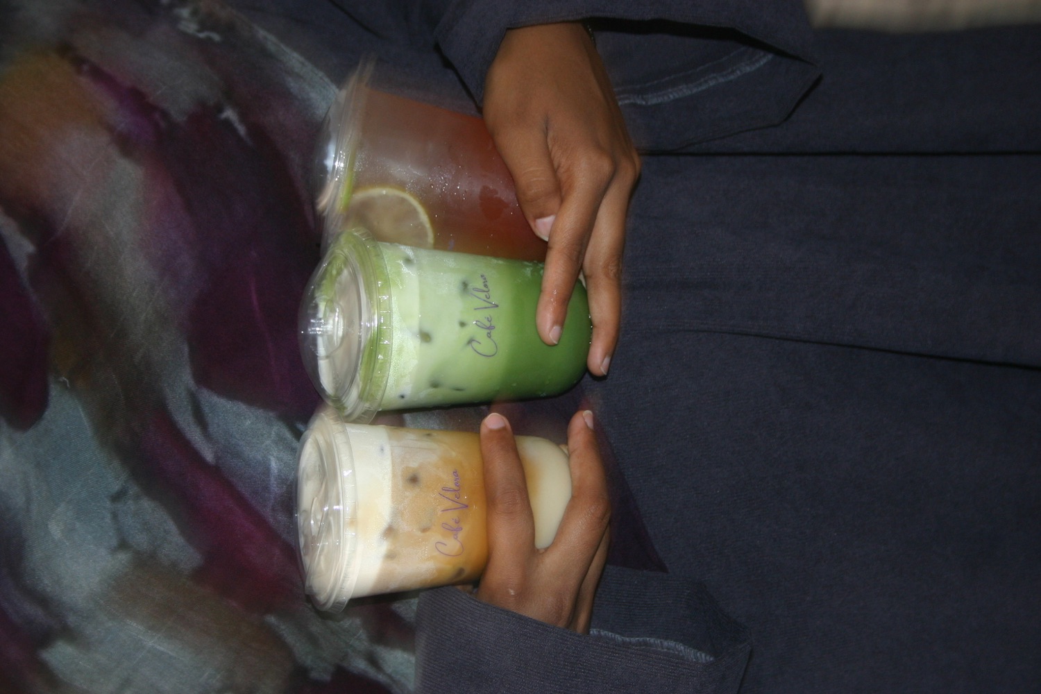 Guests holding three branded Café Velora drinks together