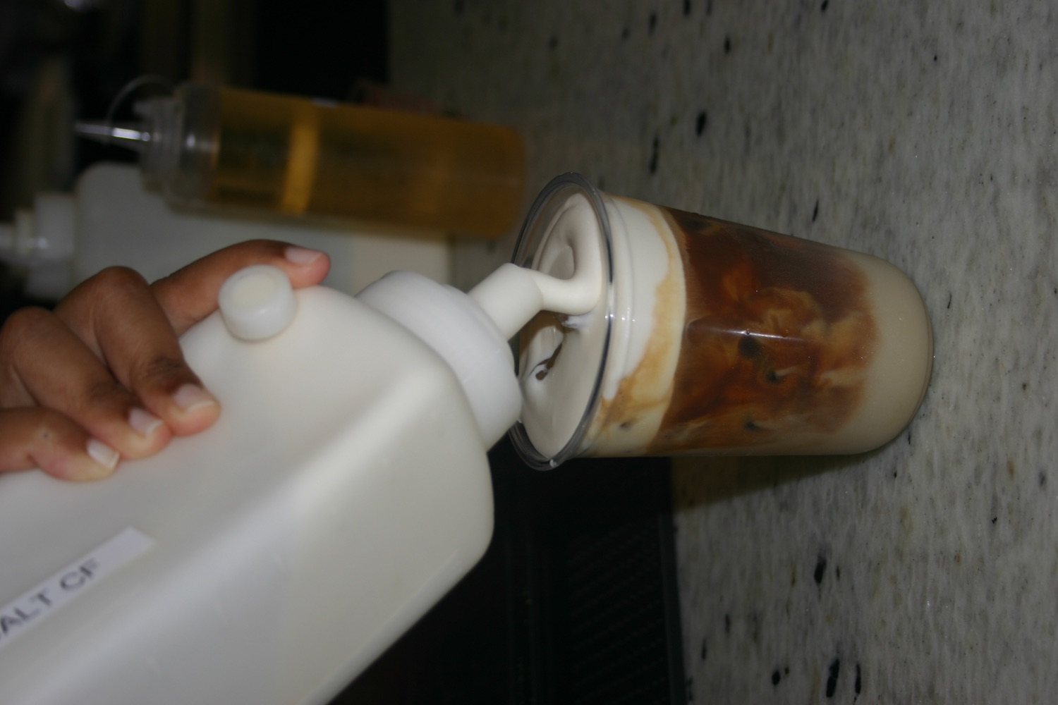 Cold foam being poured over an iced latte