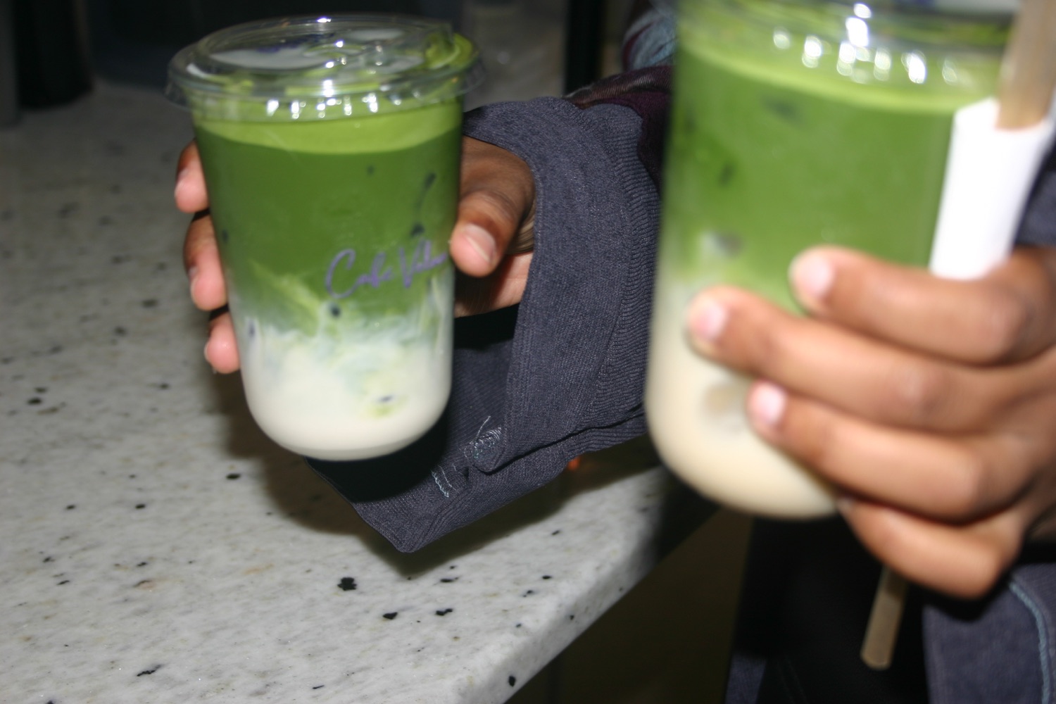 A Café Velora matcha drink handed to an event guest